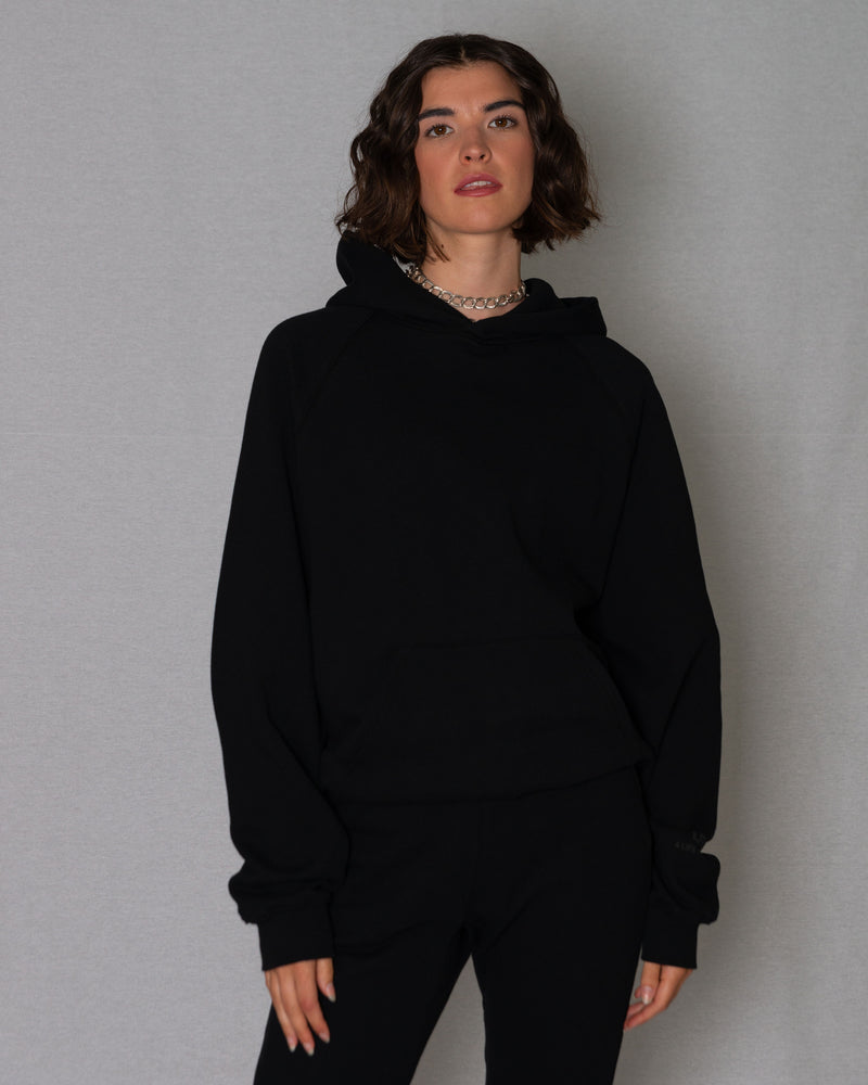 Woman wearing a match all black sweatsuit - oversized hoodie and sweatpants