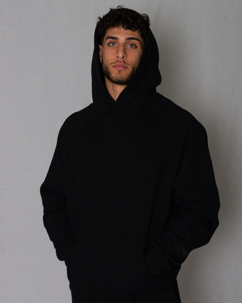 Man wearing a black oversized hoodie with the hood up